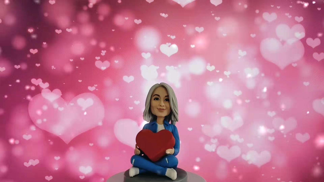 Custom bobblehead figurine of woman in blue holding heart, pink heart background