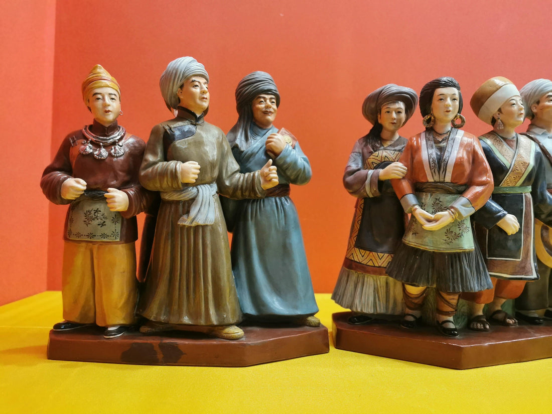 Handmade custom figurines of people in traditional attire on a yellow surface with red background