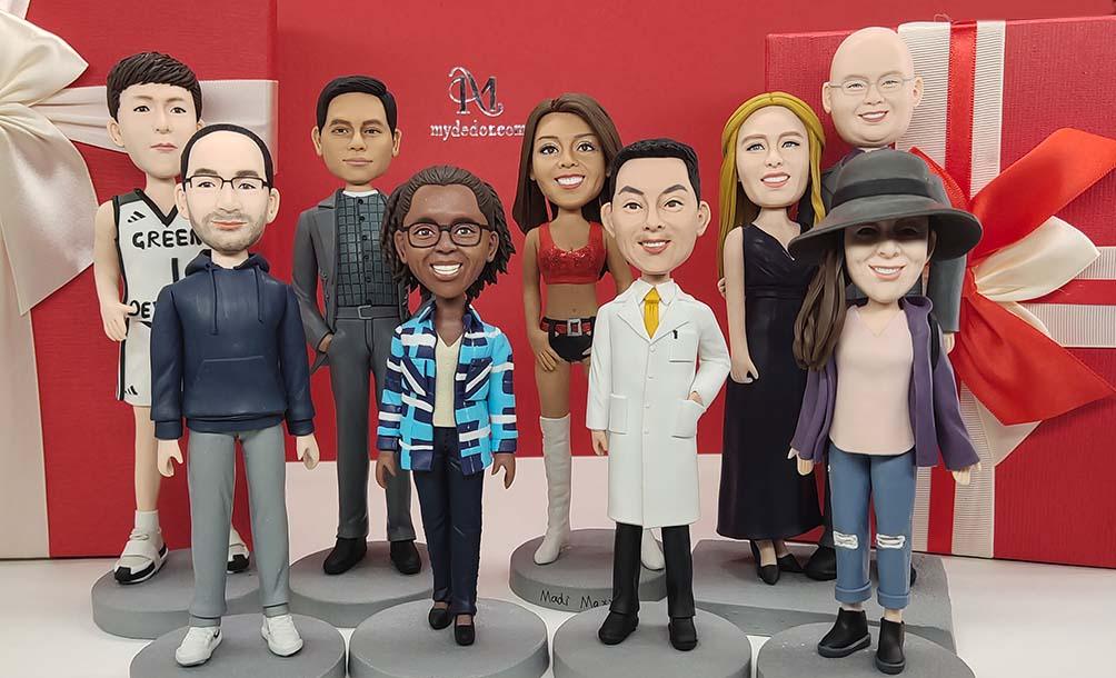Custom handmade bobblehead figurines of diverse people in front of red gift boxes with bows
